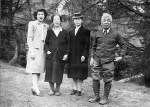 Black and white photo of three women and a man, all of Japanese descent, standing in a garden